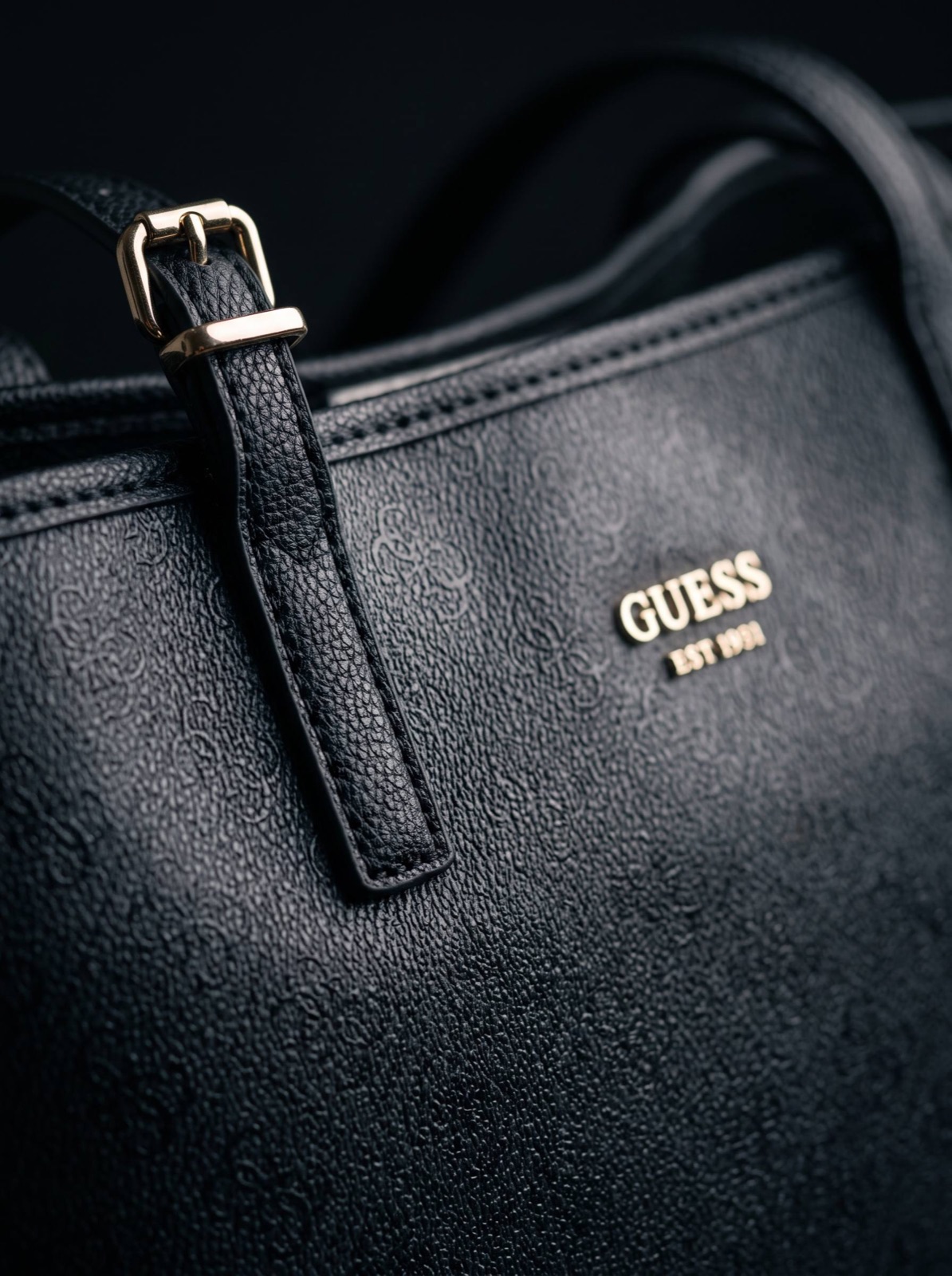 Крупный план фурнитуры и логотипа Guess на чёрной коже